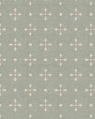 Papel mural Clementine Star verde salvia con estrellas y círculos crema en un rincón de estudio infantil con escritorio de madera.
